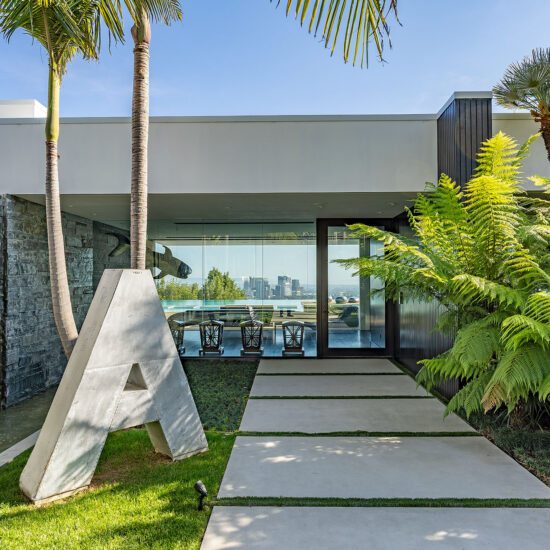 Modern entrance with a large stone letter 'A' and tropical plants.
