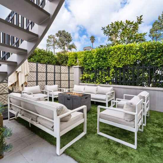 Modern outdoor seating area with white furniture and greenery.