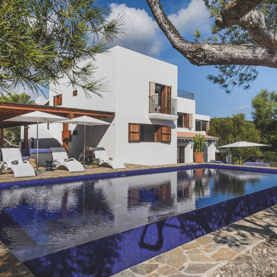 Modern white house with a sleek infinity pool surrounded by trees.