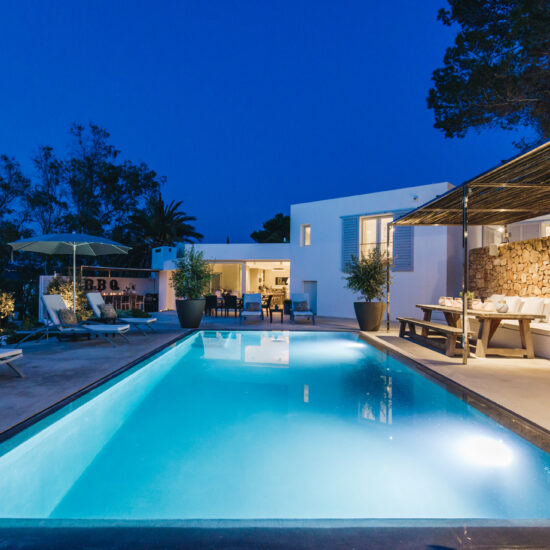 Modern house with illuminated swimming pool at dusk.