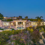 Luxurious beachfront villa illuminated at dusk with stunning ocean views.