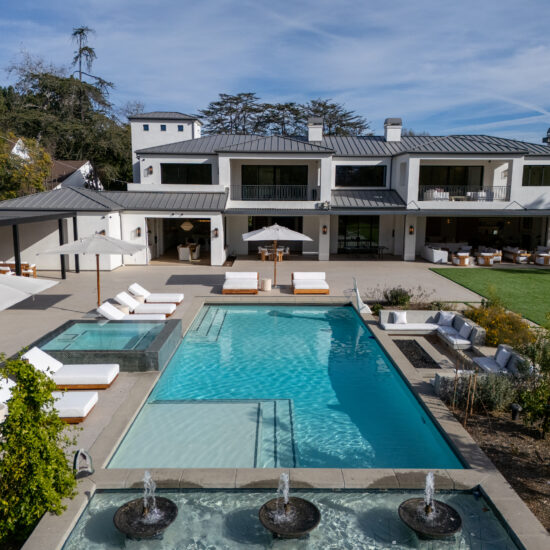 Modern luxury mansion with a large swimming pool and outdoor seating area.