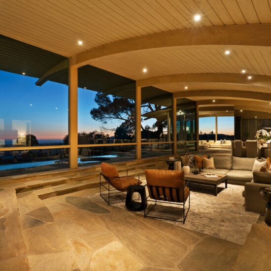 Luxurious living room with panoramic views and modern furnishings at sunset.