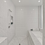 Minimalist white bathroom with marble surfaces and recessed lighting.