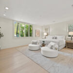 Bright living room with modern white furniture and large windows.