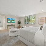 Bright modern bedroom with large windows and neutral decor.