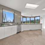 Modern curved kitchen with large windows and scenic mountain views.