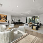 Modern living room with elegant white and gold accents and large abstract art.