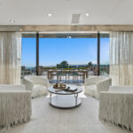 Luxurious living room with panoramic city views through large glass doors.