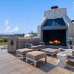 Outdoor fireplace with modern seating on a sunny rooftop patio.
