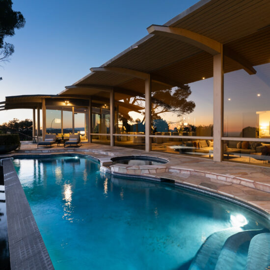 Modern house with a lit swimming pool at dusk.
