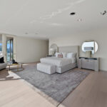 Spacious modern bedroom with large windows and neutral tones.